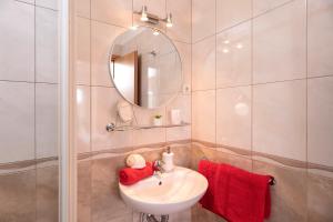 a bathroom with a sink and a mirror and red towels at Villa Fio - Rooms & Studio in Hvar