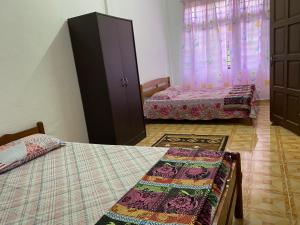 a bedroom with two beds and a dresser and curtains at Homestay Taman Maktab Pengkalan Chepa in Pengkalan Cepa