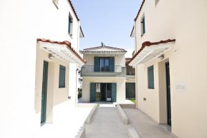 a white house with a hallway between two buildings at Anemos Villas in Mitika