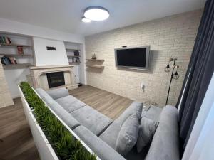 uma sala de estar com um sofá e uma televisão numa parede de tijolos em Family House FreeДом em Sinemorets