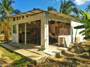 Casa pequeña con porche con palmeras en Aldea Playa Real, en Moñitos