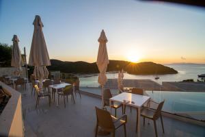 a restaurant with tables and umbrellas with the sunset at Sivota Deamaris Luxury Boutique Hotel in Syvota