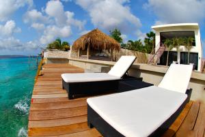 ein Holzsteg mit zwei Stühlen und einer Hütte auf dem Wasser in der Unterkunft OCEANFRONT VILLA WITH ACCES CARIBBEAN SEA in Kralendijk