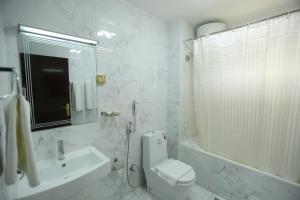 a white bathroom with a toilet and a sink at Panorama Hotel Bur Dubai in Dubai