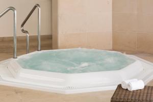 a bath tub with blue water in a bathroom at Hotel Dom Goncalo & Spa in Fátima