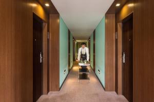 a man walking down a hallway with green walls at Hotel Dom Goncalo & Spa in Fátima