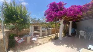 patio z fioletowymi kwiatami, stołami i krzesłami w obiekcie Can Xumeu Miquel w mieście Sant Ferran de Ses Roques