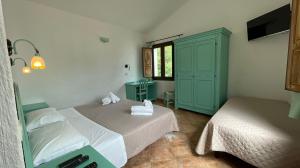 a bedroom with two beds and a green cabinet at Cort'e Nastasj in Tertenìa