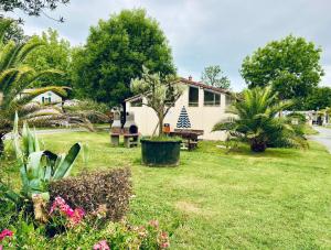 a house in a yard with flowers and plants at Cosy Lili - Mobilhome MANDARINE - Proche océan in Saint-Georges-de-Didonne