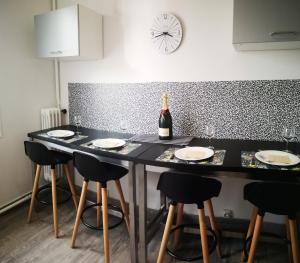 eine Küche mit einem Tisch mit Stühlen und einer Flasche Wein in der Unterkunft F3 proche centre-ville - Cote Blatin in Clermont-Ferrand