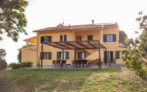 a large yellow house with tables and chairs at Agriturismo Podere La Maestà in Rosignano Marittimo