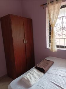 a bedroom with a bed and a cabinet and a window at Hakuna Matata Holiday Homes Goa Entire Apartment 1BHK in Baga