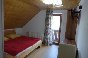 a bedroom with a red bed and a window at BOOA Rooms Irena in Bohinj