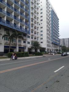 a person riding a motorcycle down a street with a large building at MOA Rental in Manila