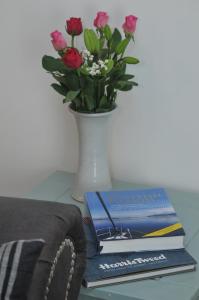 No5 Esplanade Court, Stornoway Town Centre في ستورنووي: طاولة مع مزهرية مع كتاب وزهور