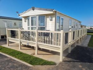 a mobile home with a porch and a deck at 8 BERTH DELUXE CARAVAN Pg156 GOLDEN PALM CHAPEL ST LEONARDS in Chapel Saint Leonards