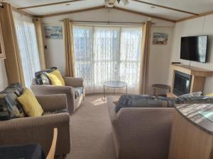 a living room with couches and a flat screen tv at 8 BERTH DELUXE CARAVAN Pg156 GOLDEN PALM CHAPEL ST LEONARDS in Chapel Saint Leonards