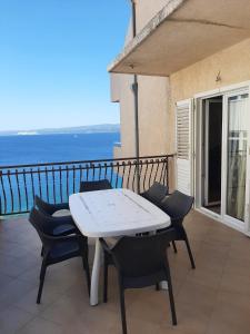 a table and chairs on a balcony with the ocean at Apartmani Karla in Dugi Rat