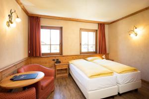 a bedroom with two beds and a table and a desk at Hotel La Pastorella in Livigno