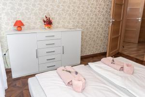 1 dormitorio con cómoda blanca y zapatillas rosas en una cama en Ruben Vendégház en Demjén