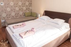 1 cama blanca grande con 2 toallas rosas. en Ruben Vendégház en Demjén