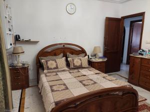 ein Schlafzimmer mit einem großen Holzbett und zwei Nachttischen in der Unterkunft jolie appart au centre urbain nord in Tunis