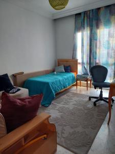 ein Schlafzimmer mit einem Bett, einem Sofa und einem Stuhl in der Unterkunft jolie appart au centre urbain nord in Tunis