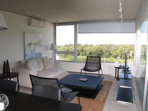 Faros de Carrasco Apartments في مونتيفيديو: غرفة معيشة مع أريكة وطاولة