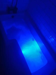 Una bañera con luz azul en un baño. en Withnell Stays - Apartment Six, en Blackpool