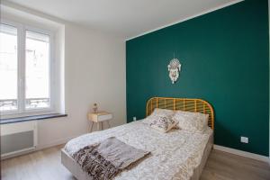 una camera da letto con una parete verde e un letto di Faubourg des voyageurs n°6 a Saran