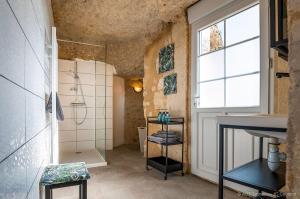 een badkamer met een douche, een wastafel en een raam bij La cavée du coteau, petit cocon troglodytique in Vouvray