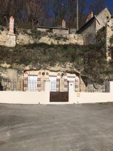 una valla blanca con una puerta delante de un edificio en La cavée du coteau, petit cocon troglodytique en Vouvray