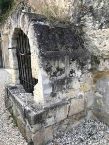 Una vieja pared de ladrillo con una rejilla. en La cavée du coteau, petit cocon troglodytique en Vouvray