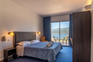 a hotel room with a bed and a view of the water at Hotel Hibiscus in Propriano