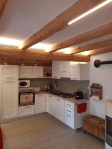 uma cozinha com armários brancos e tectos em madeira em Appartamento con terrazza - Aymavilles em Aymavilles