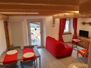 uma sala de estar com um sofá vermelho e uma mesa em Appartamento con terrazza - Aymavilles em Aymavilles