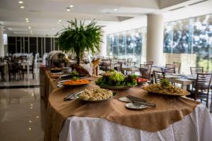 una mesa larga con platos de comida. en Nobile Hotel Convention Ciudad Del Este en Ciudad del Este