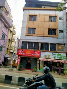 a man riding a motorcycle in front of a building at S K RESIDENCY in Bangalore