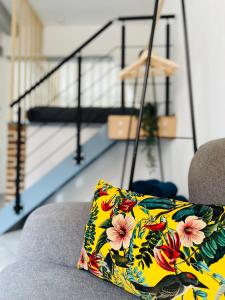 a pillow on a couch with a staircase in the background at BE MY APPARTS, Studio de charme "LE CARILLON", DOUAI, Coeur de ville in Douai