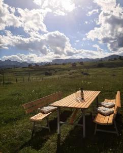 a picnic table with a bottle of wine and two benches at Guest House Nena in Žabljak
