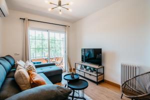 salon z niebieską kanapą i telewizorem w obiekcie tuGuest Halcón Apartment w Grenadzie