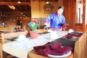 uma mulher a preparar comida numa mesa num restaurante em Rema Resort em Paro