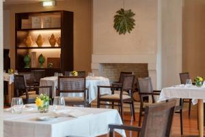 a dining room with white tables and chairs and a fireplace at Hotel Dom Goncalo & Spa in Fátima