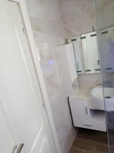 La salle de bains blanche est pourvue d'un lavabo et d'un miroir. dans l'établissement luxy Appartement, Smir Park, M’diq ,TETOUAN, à Marina Smir