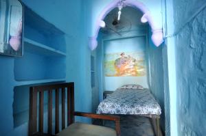 a blue room with a bed and a painting on the wall at Cosy Guest House in Jodhpur
