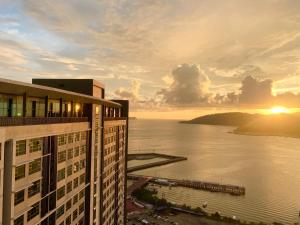 - une vue sur un bâtiment et l'océan au coucher du soleil dans l'établissement Sunset Seaview Vacation Condos @ Jesselton Quay, à Kota Kinabalu