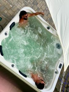 un homme est dans une baignoire jacuzzi dans l'établissement Alpin House Colibita, à Colibiţa