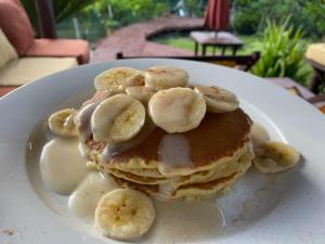 a stack of pancakes with syrup and bananas on a plate at Salt Lake Lodge in Savusavu
