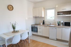 a kitchen with white cabinets and a table and a clock at Apartman Boem in Trogir