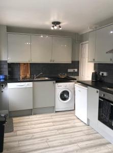 a kitchen with white cabinets and a washing machine at Welsh Getaway Home No 1 - 10 mins to Bike Park Wales in Merthyr Tydfil